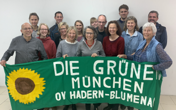 Gruppe von OV-Mitgliedern, die ein Grüns Tuch mit dem Text Die Grünen München OV Hadern-Blumenau sowie einer gemalten Sonnenblume halten.